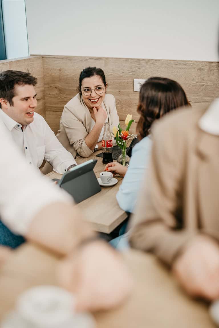 Geschäftsleute im Gespräch bei einem Meeting, lachend und in entspannter Atmosphäre.