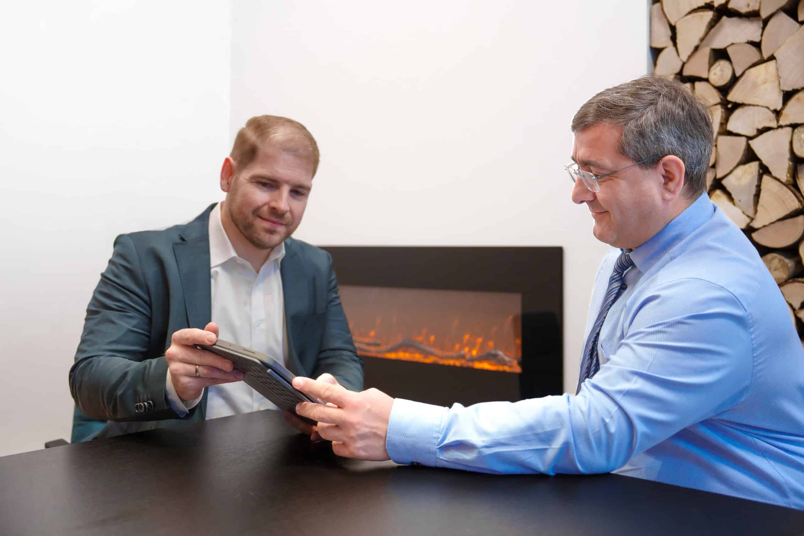 Zwei Männer im Gespräch bei einem Beratungstermin, einer zeigt auf ein Dokument.