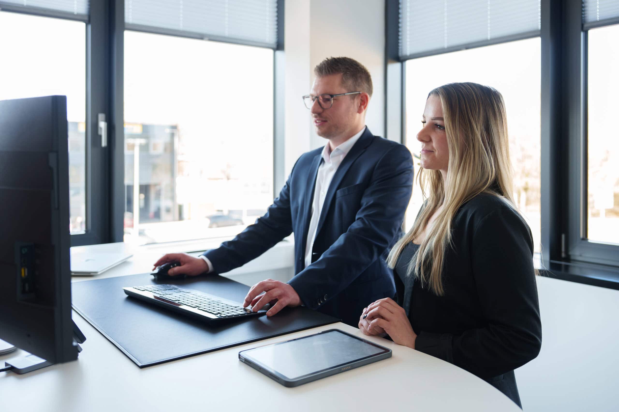 Zwei Geschäftsleute bei einem Meeting im modernen Büro mit großen Fenstern.