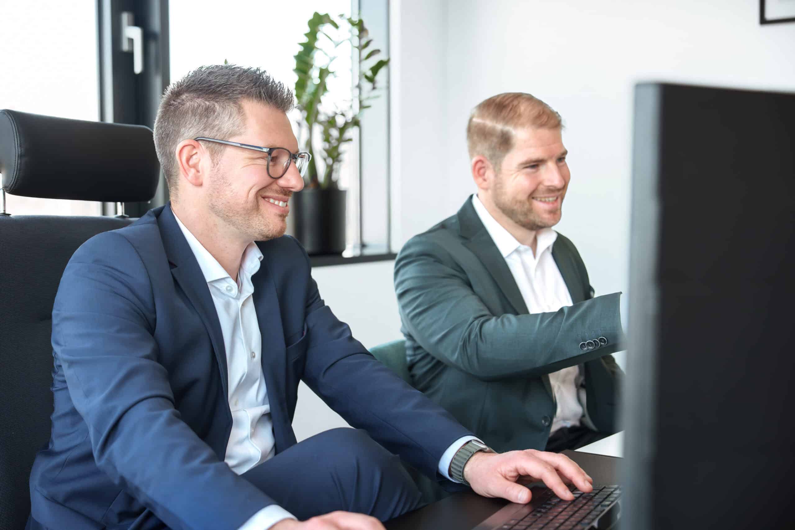 Zwei Männer im Anzug bei einem Meeting im modernen Büro.
