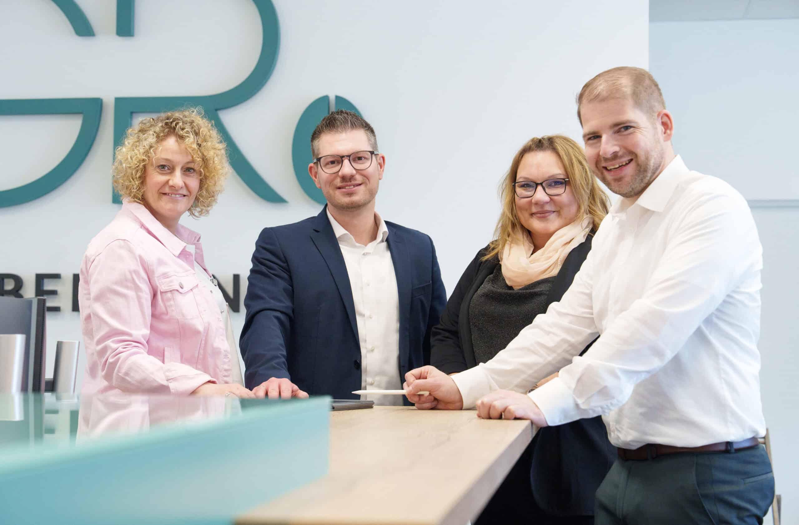 Mitarbeiter des Teams bei der Arbeit im Büro, lächelnd und professionell, mit moderner Arbeitsumgebu.